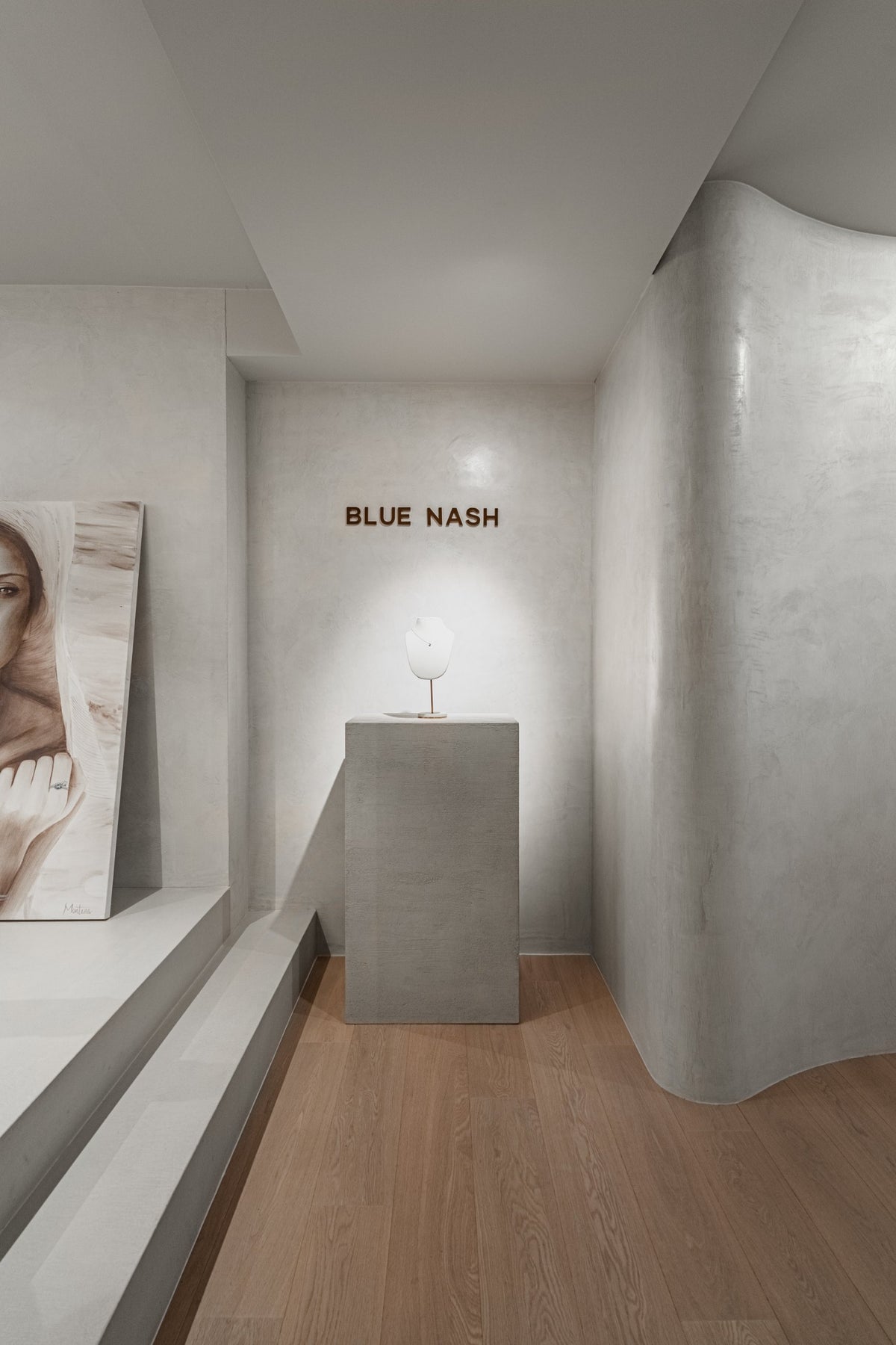 The Bluenash showroom in Antwerp: a pedestal under the gold Blue Nash letters, beside a curved plaster wall